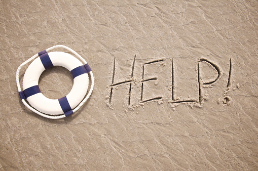 Help! message written in textured sand features a lifesaver