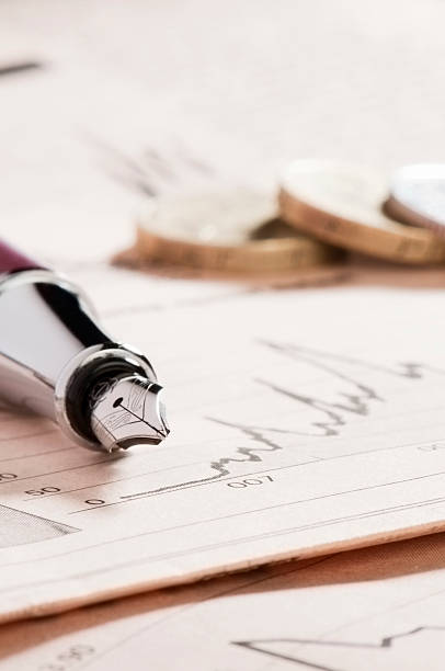 istock Fountain pen on graph in newspaper with coins 183335250