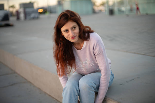 istock Young woman sitting and smiling in a un urban context 1833372744