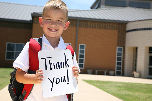 istock Elementary Student Holding Thank You Sign in Front of School 183337729