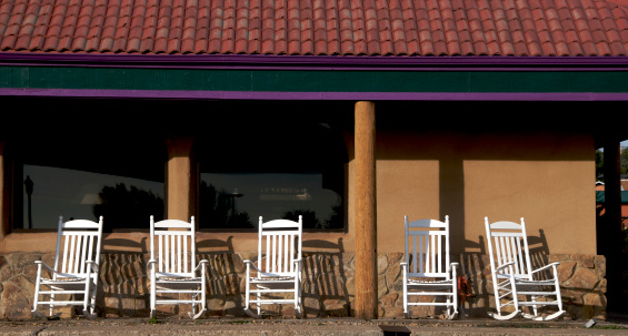 Five rocking chairs on the porch of a commercial establishment.