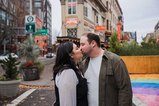 A authentic happy young multiracial couple having a coffee date in Downtown Portland Oregon. The season is autumn with colorful leafs around the city streets and buildings.