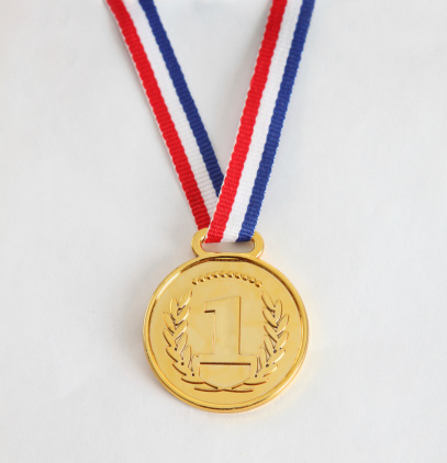 Gold medal with multicolored ribbon on blue background, copy space for text.