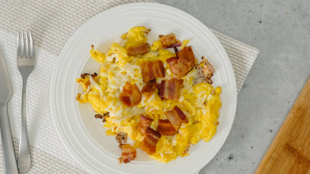 istock English breakfast. Scrambled eggs fried with bacon and cheese. Meal on a plate, view from above 1833399018