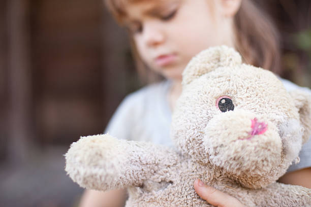 istock Sad Young Girl Holding Old, Raggedy Teddy Bear 183340244