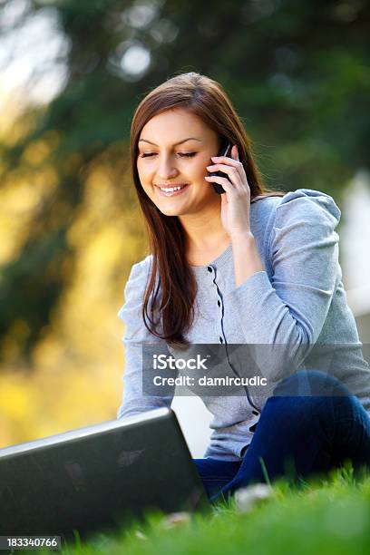 Giovane Donna Utilizzando Un Cellulare E Lavorando Al Computer Portatile - Fotografie stock e altre immagini di 20-24 anni