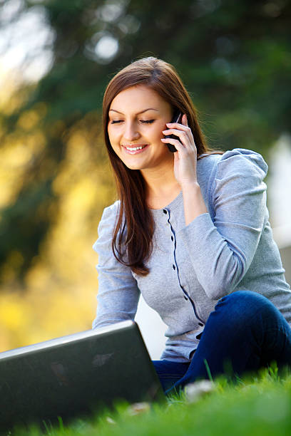 istock Young woman using cell phone and working on laptop 183340766