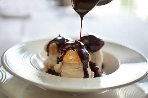 Closeup picture of profiteroles bathing in chocolate