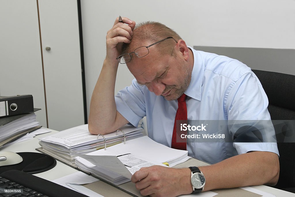 Stressed Manager "Shot at a managers office, manager in stress over brain wracking paperwork" Bureaucracy Stock Photo