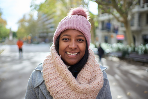 Beautiful latin woman standing in winter clothes smiling looking at the camera crossing arms