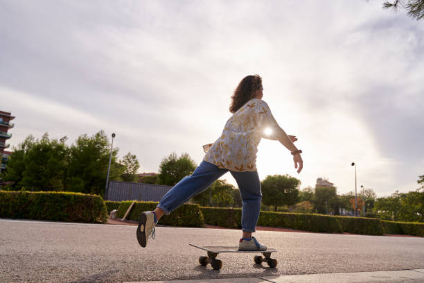 istock unrecognizable curly-haired woman propelling herself on a skateboard in backlit sunshine 1833423792