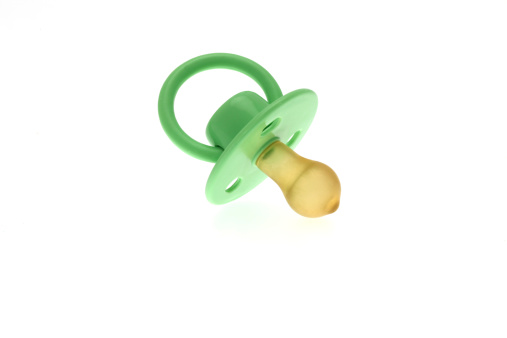 High key image of a traditional infants green dummy or pacifier taken against a white background.