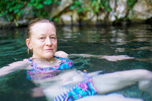 Clouse up of senior women relaxing while having in outdoors, natural hot spa refreshing therapy. It is in forest near cold river not far from Šmarjetske toplice - spa, Slovenia, Europe.