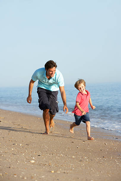istock Father And Son Running Along Beach 183343287