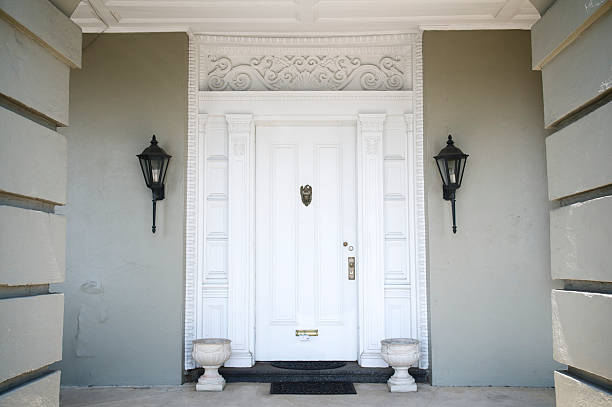 Grand entrance with traditional white door and decorative molding is framed by clean modern columns