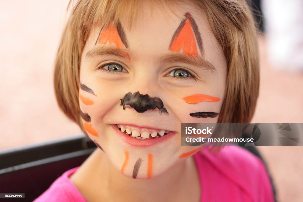 Menina com rosto é pintado como o tiger sorri para câmera - Foto de stock de Parque de diversões - Evento de entretenimento royalty-free