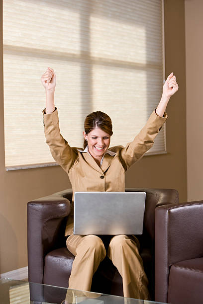 aufgeregt geschäftsfrau sitzt im sessel blick auf laptop mit ra - office chair cheering ecstatic success stock-fotos und bilder