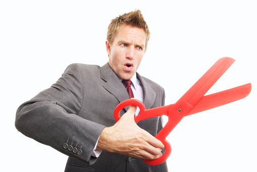 Young man businessman taking a big pair of red scissors cutting with an oversized snip