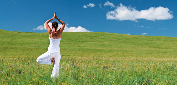 A happy young girl practicing yoga on the grass, cloudy sky background.http://bem.2be.pl/IS/outdoors_laptop_380.jpg