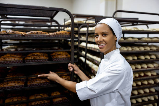 Baker moving a rack of bread trays at an industrial bakery
