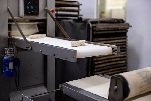 Bread dough on a conveyor belt at an industrial bakery - food processing plant concepts