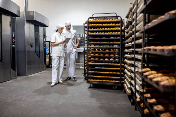 bäckerteam bei der arbeit in einer großbäckerei - industrie ofen stock-fotos und bilder