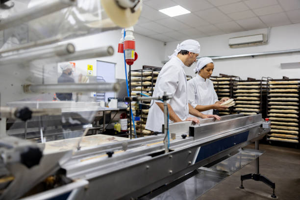 Foreman training a new worker at an industrial bakery