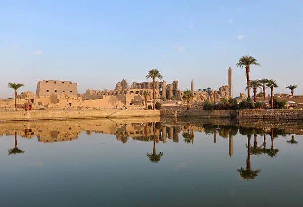 "The legendary Ancient Egyptian temple of Karnak illuminated by the golden light of dawn and reflected in the sacred lakeLuxor, EgyptThe Karnak Temple Complexaausually called Karnakaacomprises a vast conglomeration of ruined temples, chapels, pylons, and other buildings, notably the Great Temple of Amen and a massive structure begun by Pharaoh Ramses II (ca. 1391aa1351 BC). An ancient sacred lake is part of the site as well."