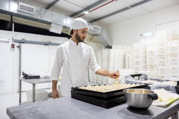 istock Baker spreading egg yolks on some bread at the bakery 1833457215
