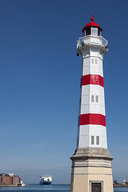 Striped lighthouse against blue sky stock photo