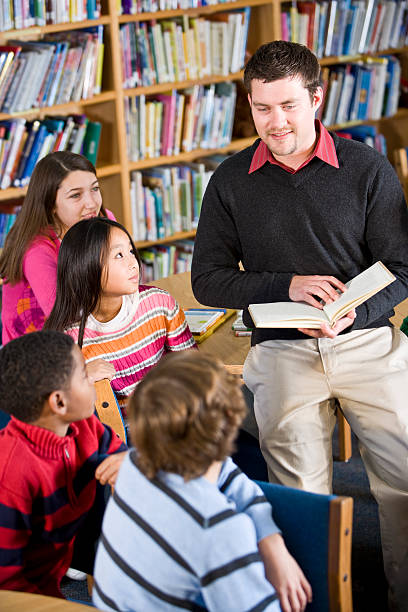 istock Teacher or librarian reading to group of children 183346567