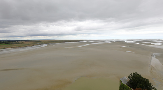 plain at low tide seen from the Abbey of Mont Saint Michel in northern France and cloudy sky