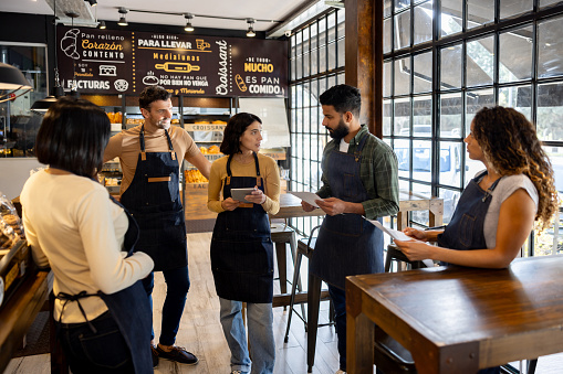 Multiracial group of workers talking in a staff meeting at a cafe and sharing ideas - small business concepts