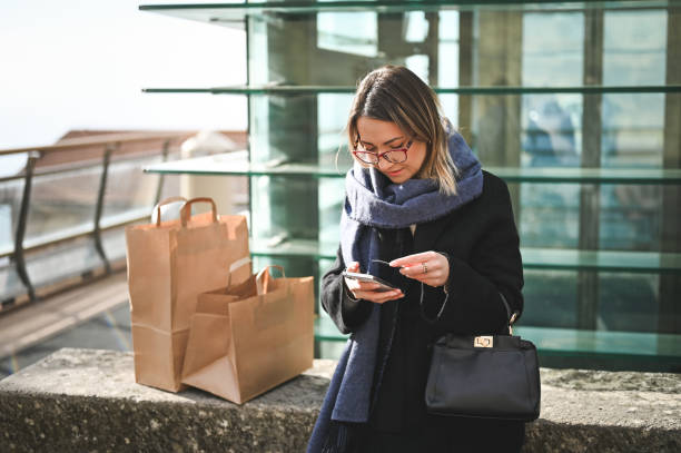 istock young woman outdoors making online payment with credit card. 1833504623
