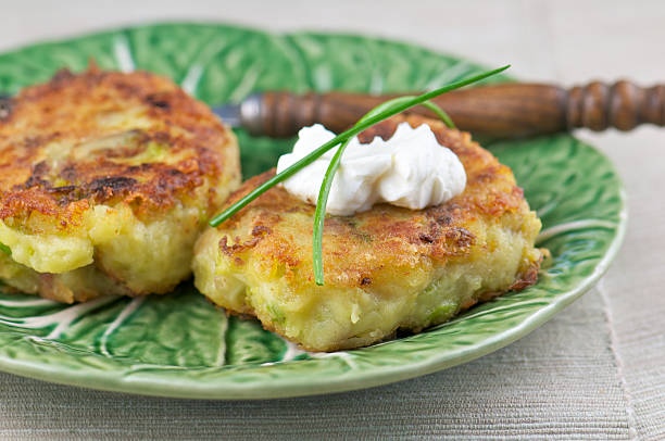Potato cakes with creme fraiche and chives on green plate with wooden utensil