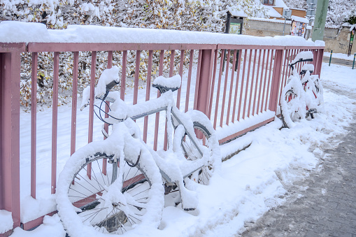 Bicycle caught in evening snow storm. Snowfall snowstorm blizzard weather warning snow forecast snow in the city bicycle covered, High quality photo