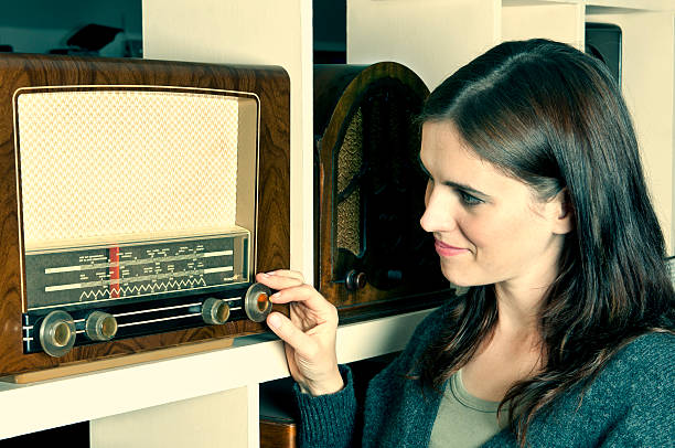 jeune femme à l'écoute à l'ancienne radio rétro - women common 40s candid photos et images de collection