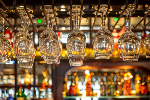 Wine glasses hanging over a bar, with a shallow depth of field Ready to use wine glasses above a bar, with selective focus wine bar counter stock pictures, royalty-free photos & images