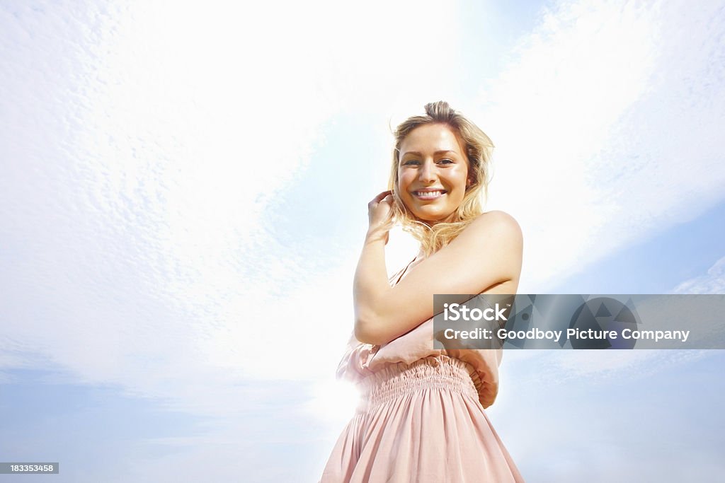 Hermosa mujer joven sonriente contra el cielo nublado - Foto de stock de 20 a 29 años libre de derechos