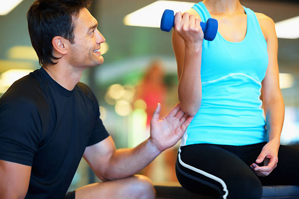 istock Personal trainer instructing woman with dumbbell 183353810