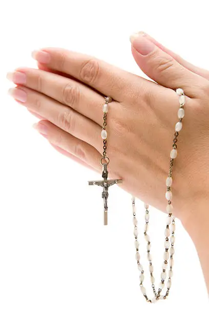 Woman praying while holding a rosary in her hands. Isolated on a white background.