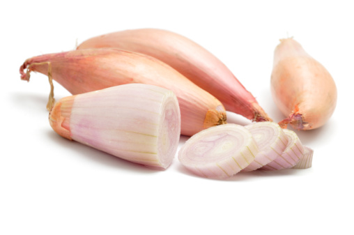 Four Shallots, one sliced isolated on a white background.