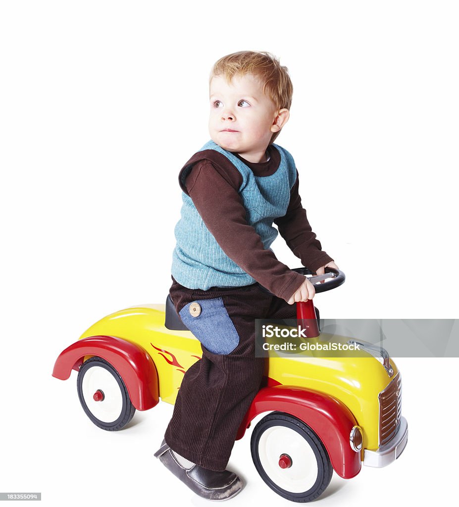 Giovane ragazzo equitazione in un auto giocattolo isolato su bianco - Foto stock royalty-free di Bambino
