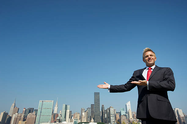 istock Smiling Businessman Gestures Toward Skyline Copy Space 183355675