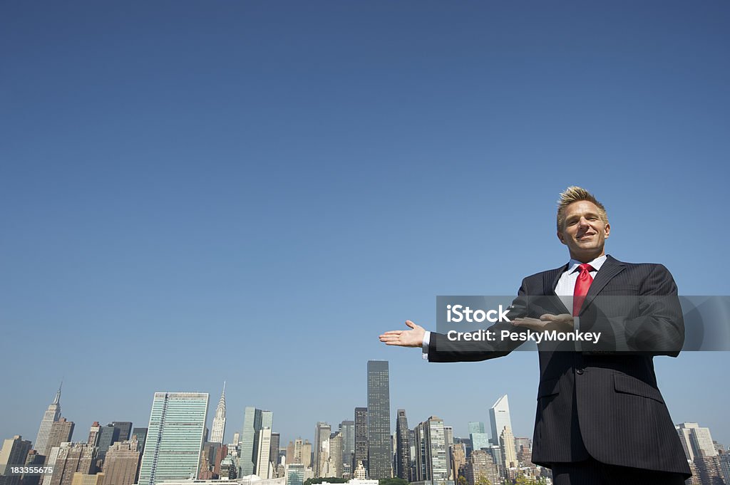 Uśmiechająca się Biznesmen gesty w kierunku Skyline Miejsce na tekst - Zbiór zdjęć royalty-free (Agent nieruchomości)