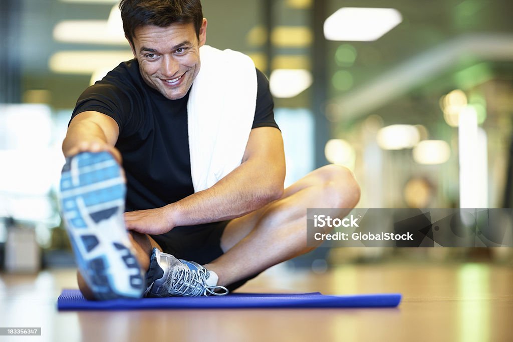 Uomo sorridente mentre fa stretching - Foto stock royalty-free di Abbigliamento sportivo