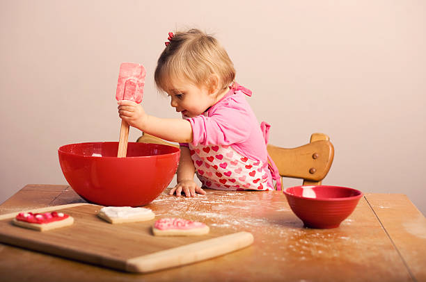 Cтоковое фото Маленькая девочка, выпечки День святого Валентина печенье в кухне