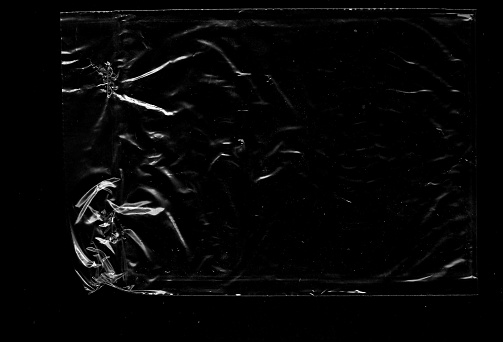 An intriguing close-up of wrinkled plastic film, showcasing its tactile and textured surface on full black background