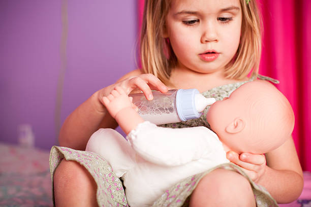 Little Girl Feeding Her Baby Doll with Bottle stock photo