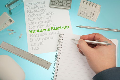 Starting a business... person writes down their plans and ideas. There are many things to consider strategy, marketing as well as legalities such as tax, insurance, employment etc. 